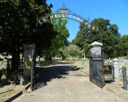 There is an elaborately decorated wrought-iron archway at the entrance of the cemetery.